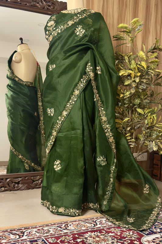 Green saree with floral patterns on a mannequin against a decorative background